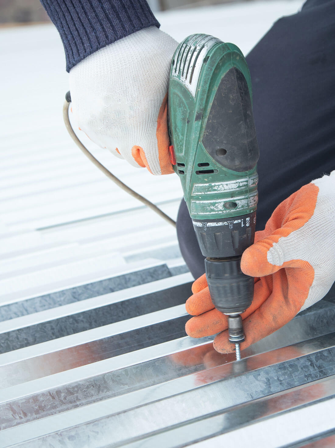 Man Installing Metal Sheet Roof By Electrical Drilling Machine.